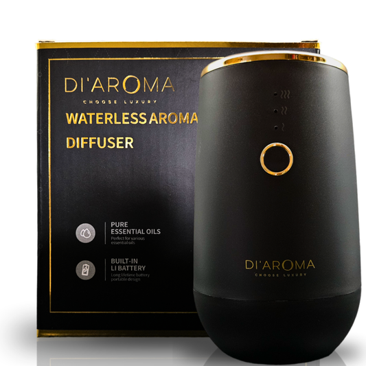 Black waterless aroma diffuser with gold accents next to its packaging on a white background